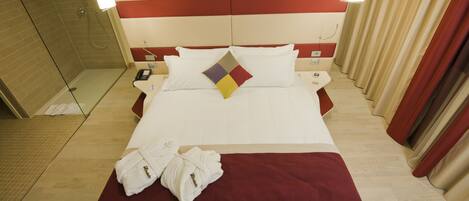 A hotel room with a large bed, a shower area, and two bedside tables with lamps.