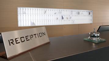 A reception desk with a sign reading "RECEPTION" and a bell on a green coaster.