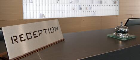 A reception desk with a sign reading "RECEPTION" and a bell on a green coaster.