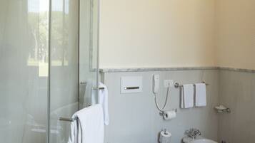 Un baño con ducha de vidrio, inodoro, bidé y lavamanos de mármol.