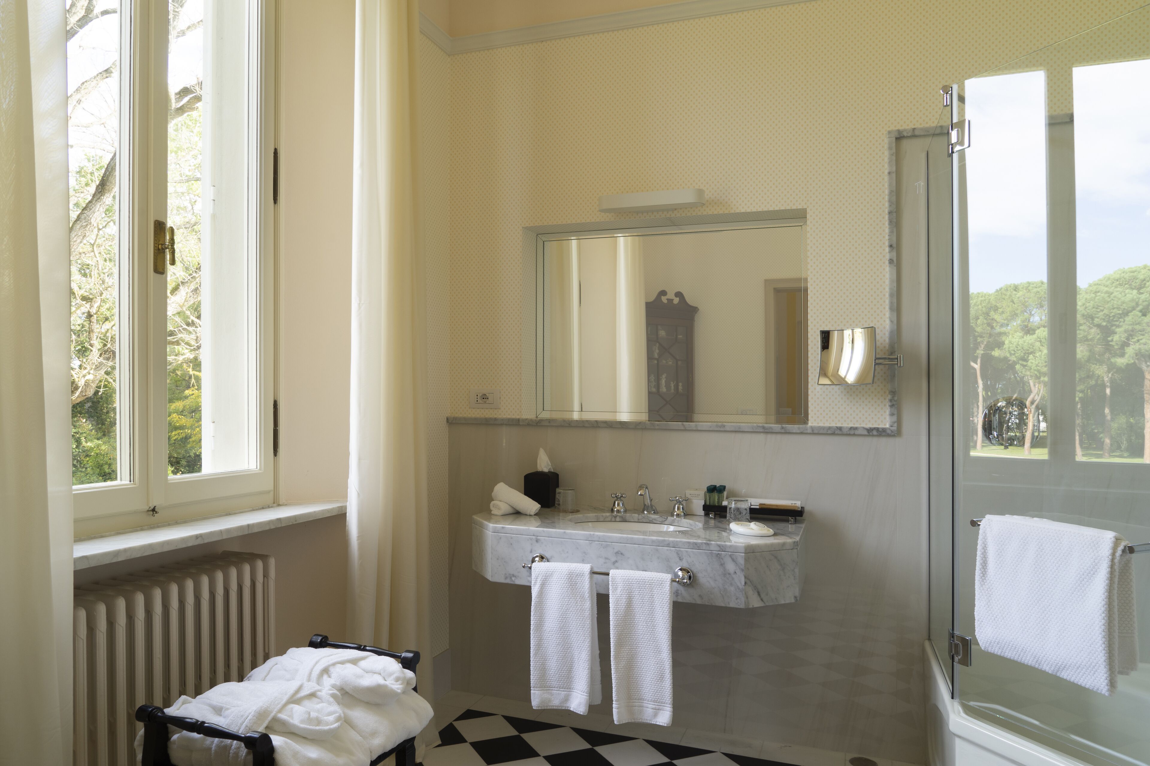 Un bagno con un'ampia finestra, un lavandino con uno specchio sopra e una zona doccia.