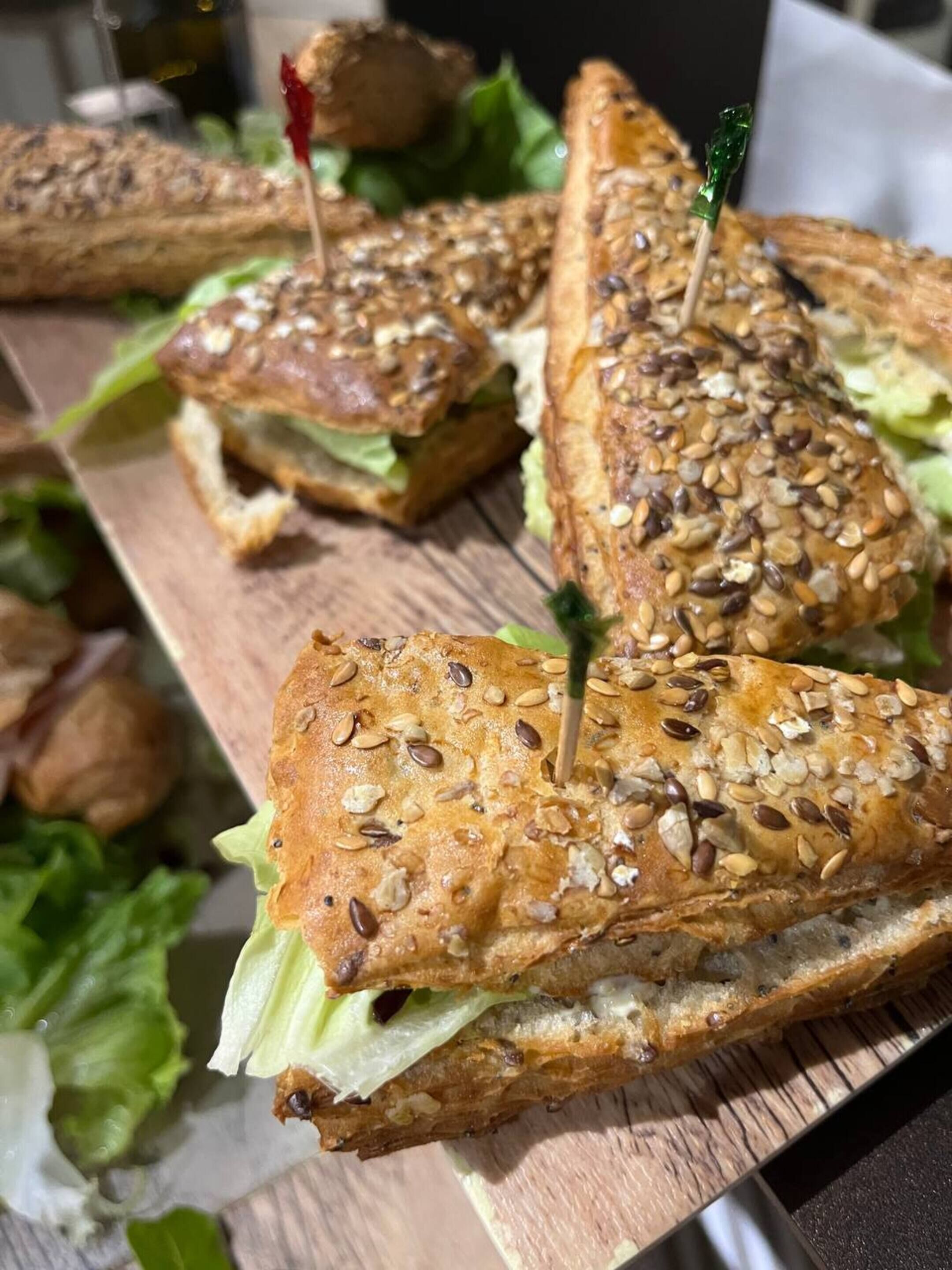 Ein Holzbrett mit mehreren Sandwiches, jedes mit einem Zahnstocher.