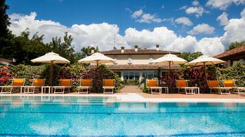 Relax by the serene pool surrounded by lush greenery and flowering plants.