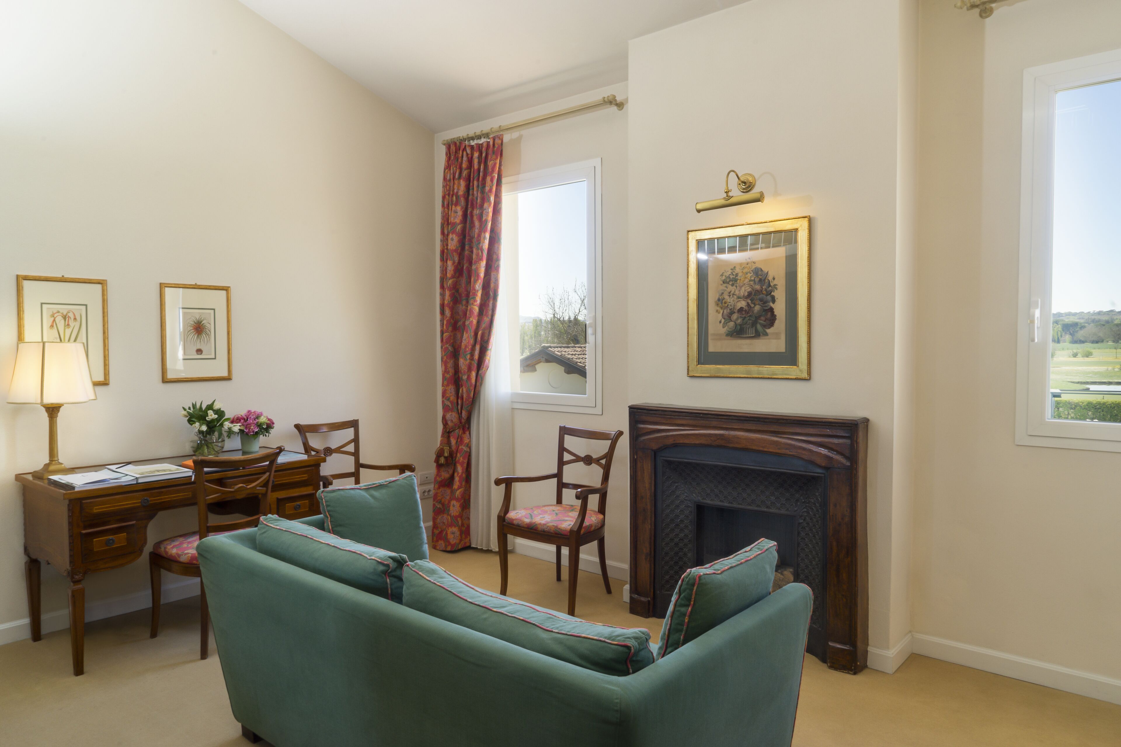 Une pièce avec une cheminée, un bureau avec des chaises, un canapé et des œuvres d’art encadrées accrochées aux murs.