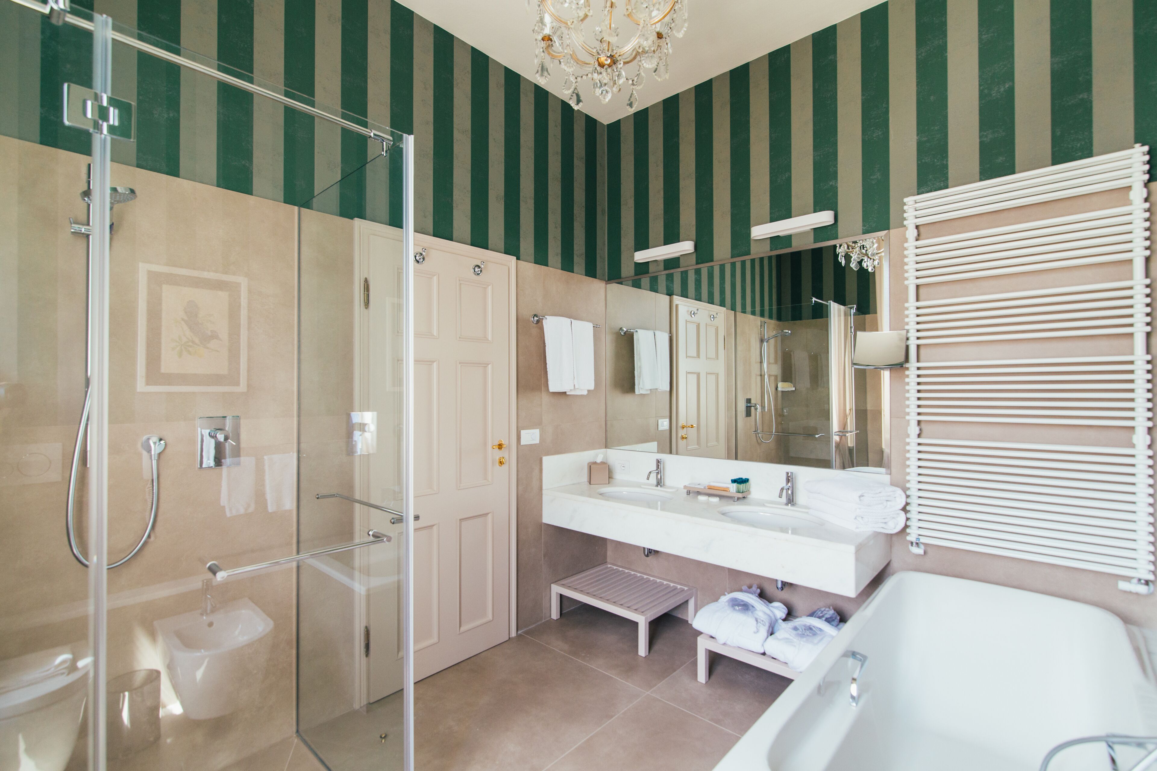 Un baño moderno con ducha envuelta en vidrio, un espejo grande, tocador con lavamanos y bañera.