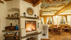A rustic interior with a fireplace, wooden beams, and a dining area with chairs and a table. - Hotel Alpenroyal (Zermatt)