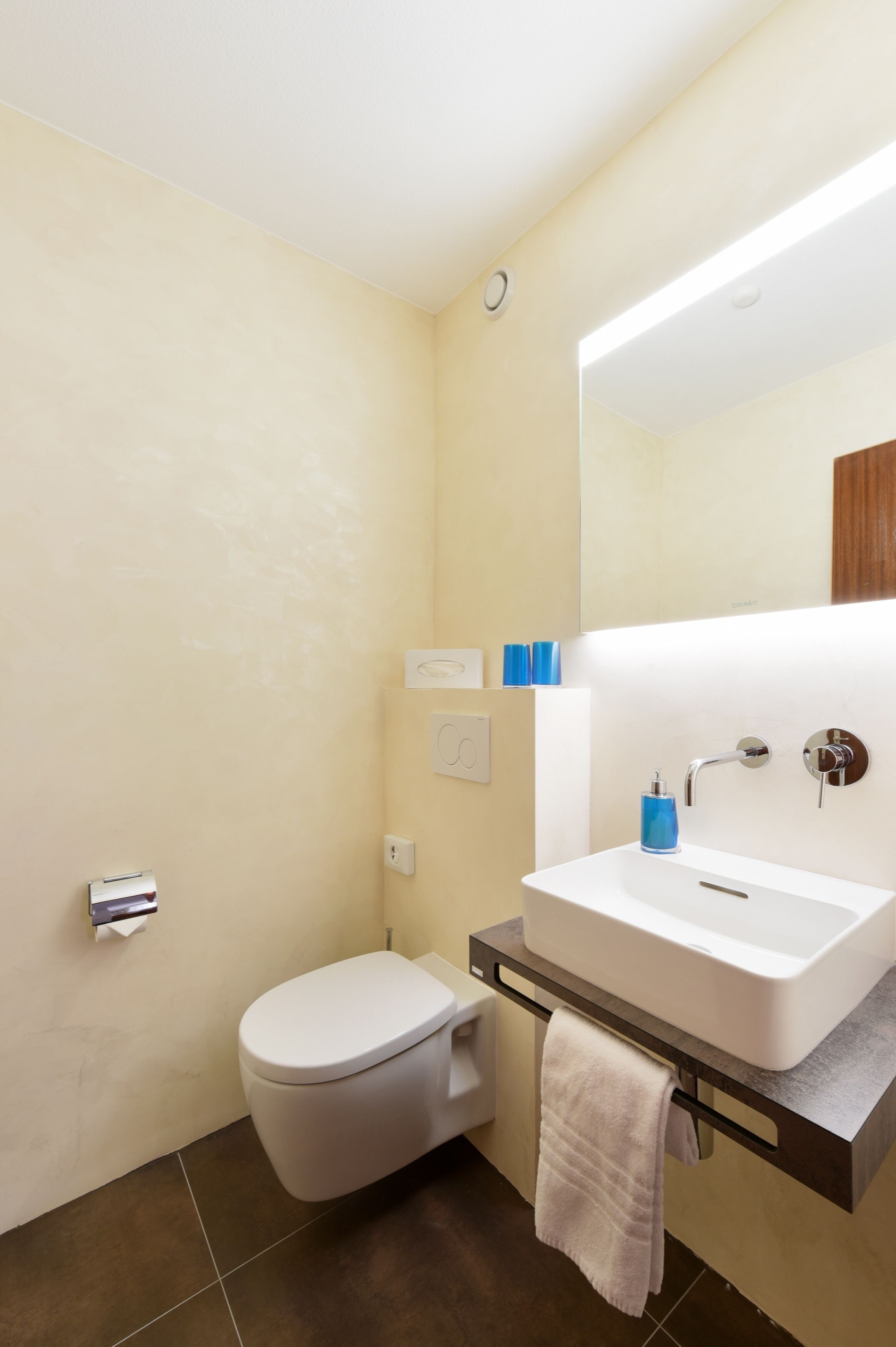 A bathroom with a toilet, sink, and mirror.