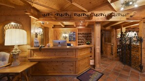 A wooden reception desk with a laptop, a lamp, and a door with a decorative metal gate. - Hotel Alpenroyal (Zermatt)