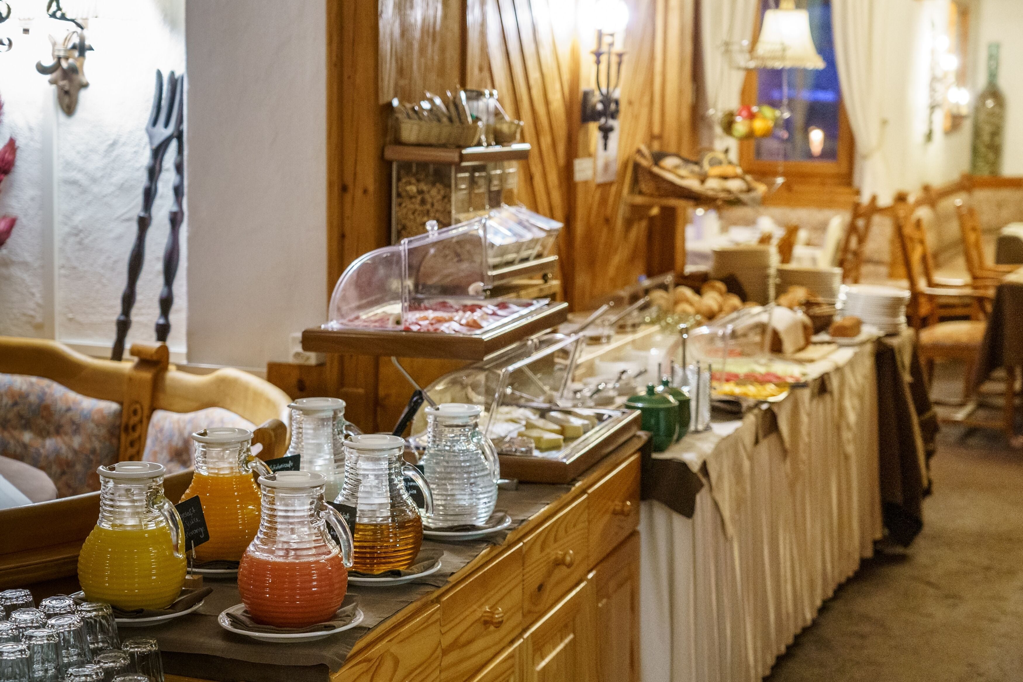 Ein Buffetbereich mit verschiedenen Speisen und Getränken, darunter eine Auswahl an Säften und eine Fleischstation.
