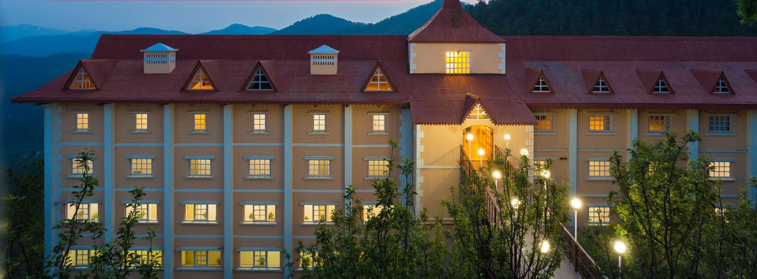 A large, multi-story hotel with a symmetrical facade, multiple windows, and a central entrance with a staircase.