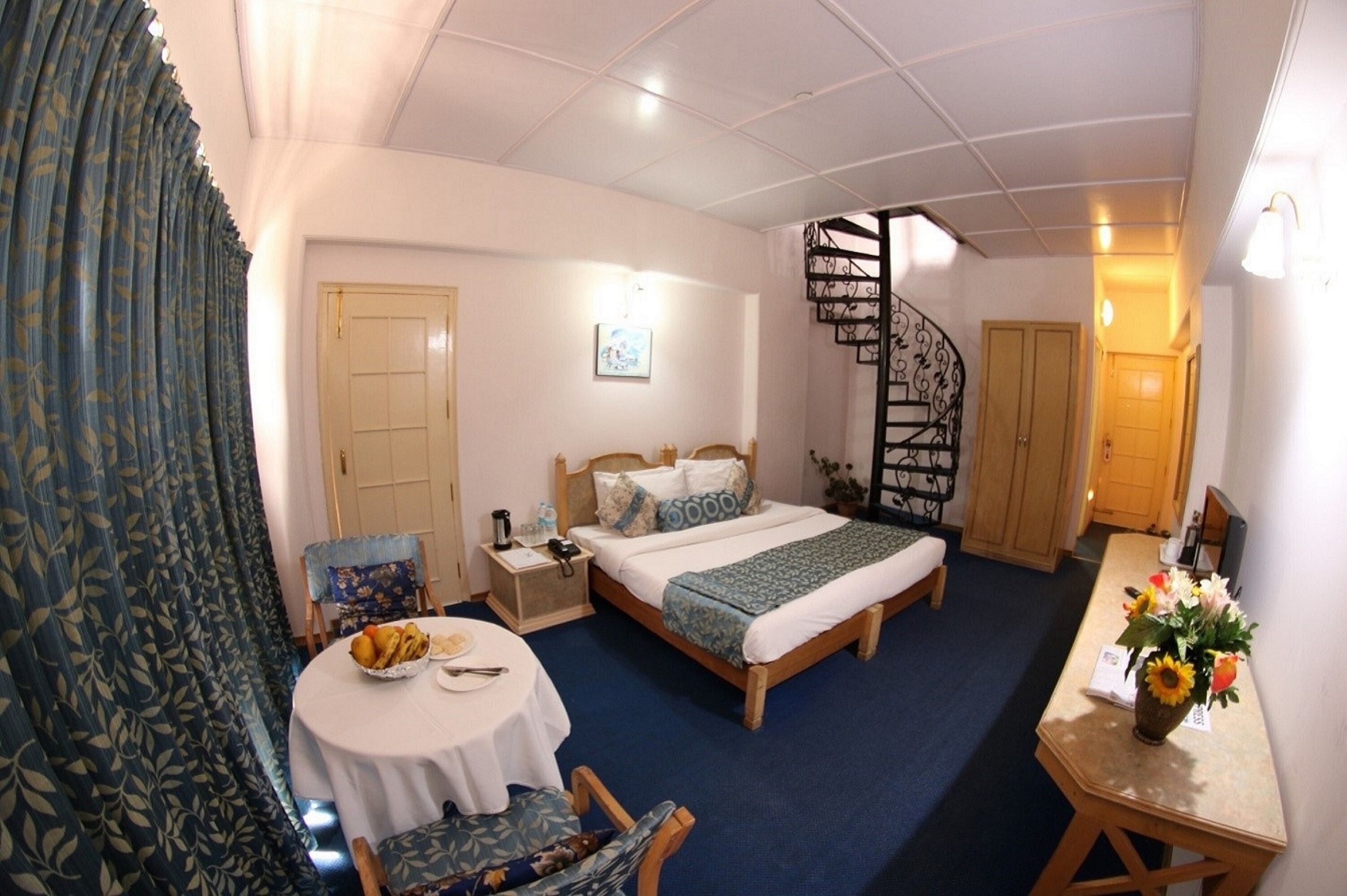 Una habitación de hotel con una cama, un escritorio, una silla, una mesa redonda y una escalera.