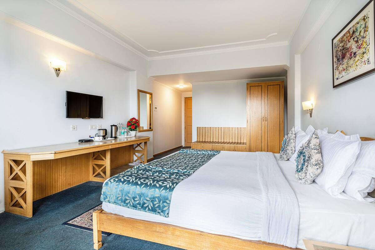 Una habitación de hotel con cama, escritorio, televisión y baño.
