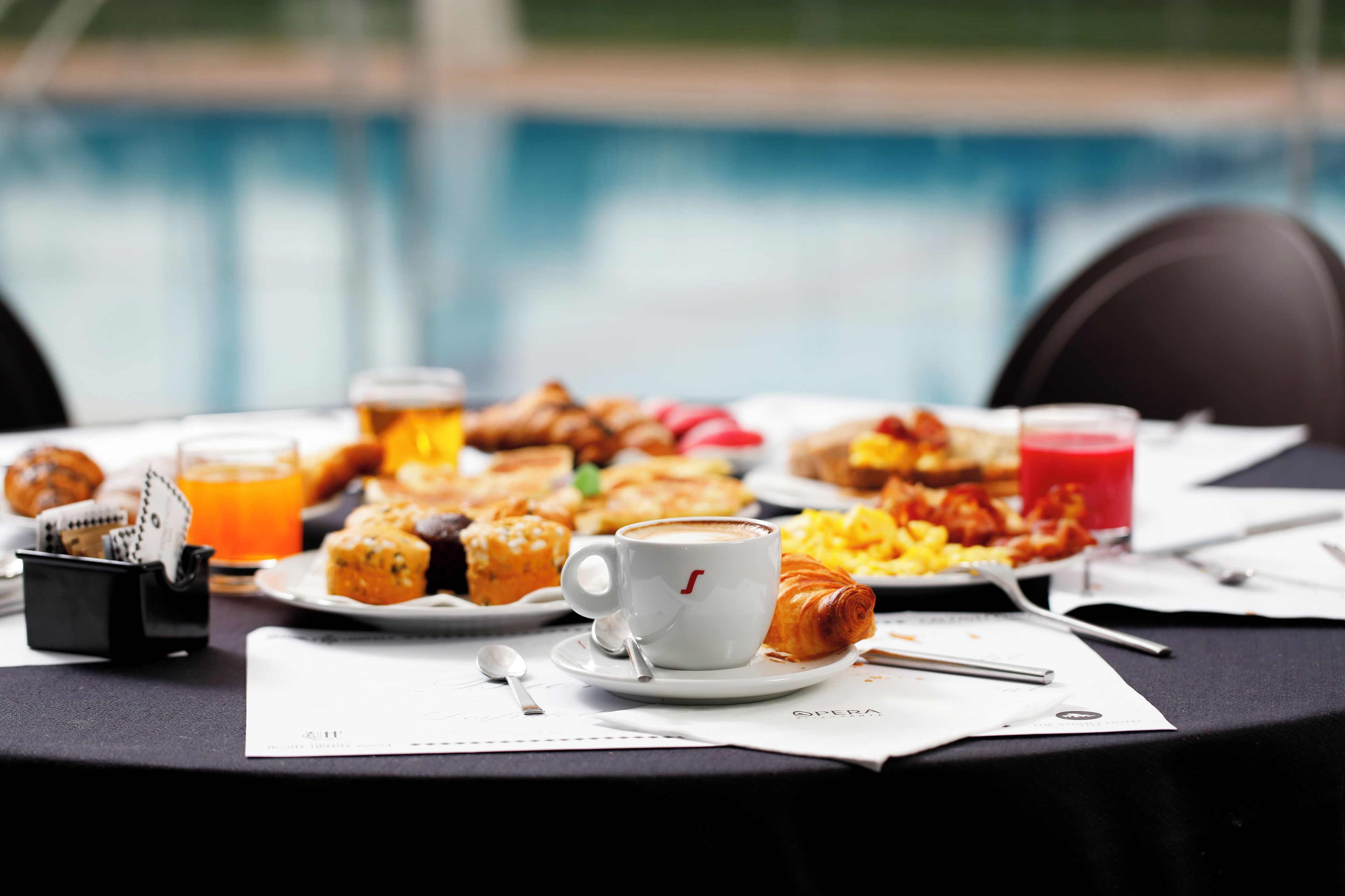 Mesa de café da manhã com croissants, doces e uma xícara de café.