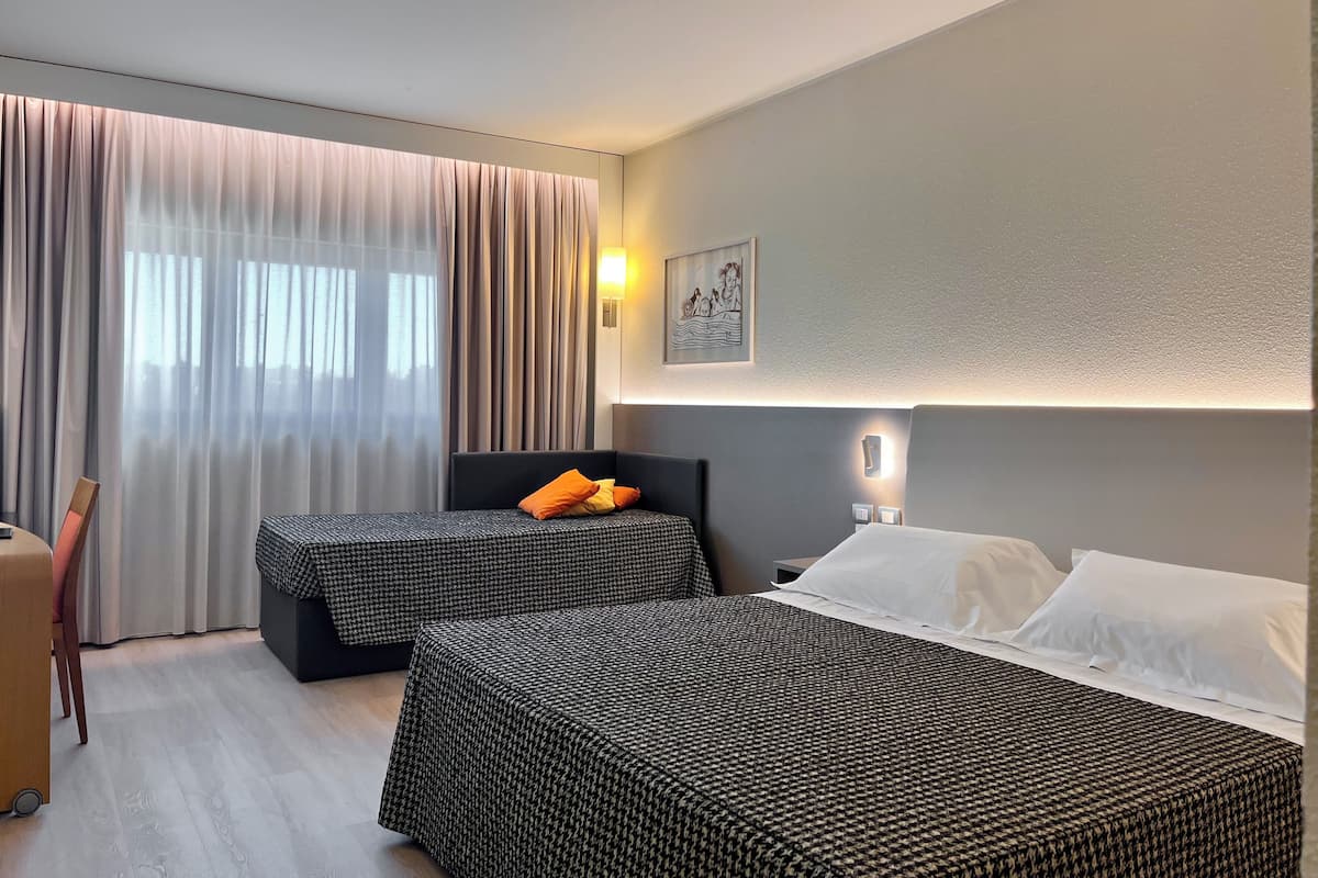Une chambre d’hôtel avec deux lits, un bureau et une chaise.