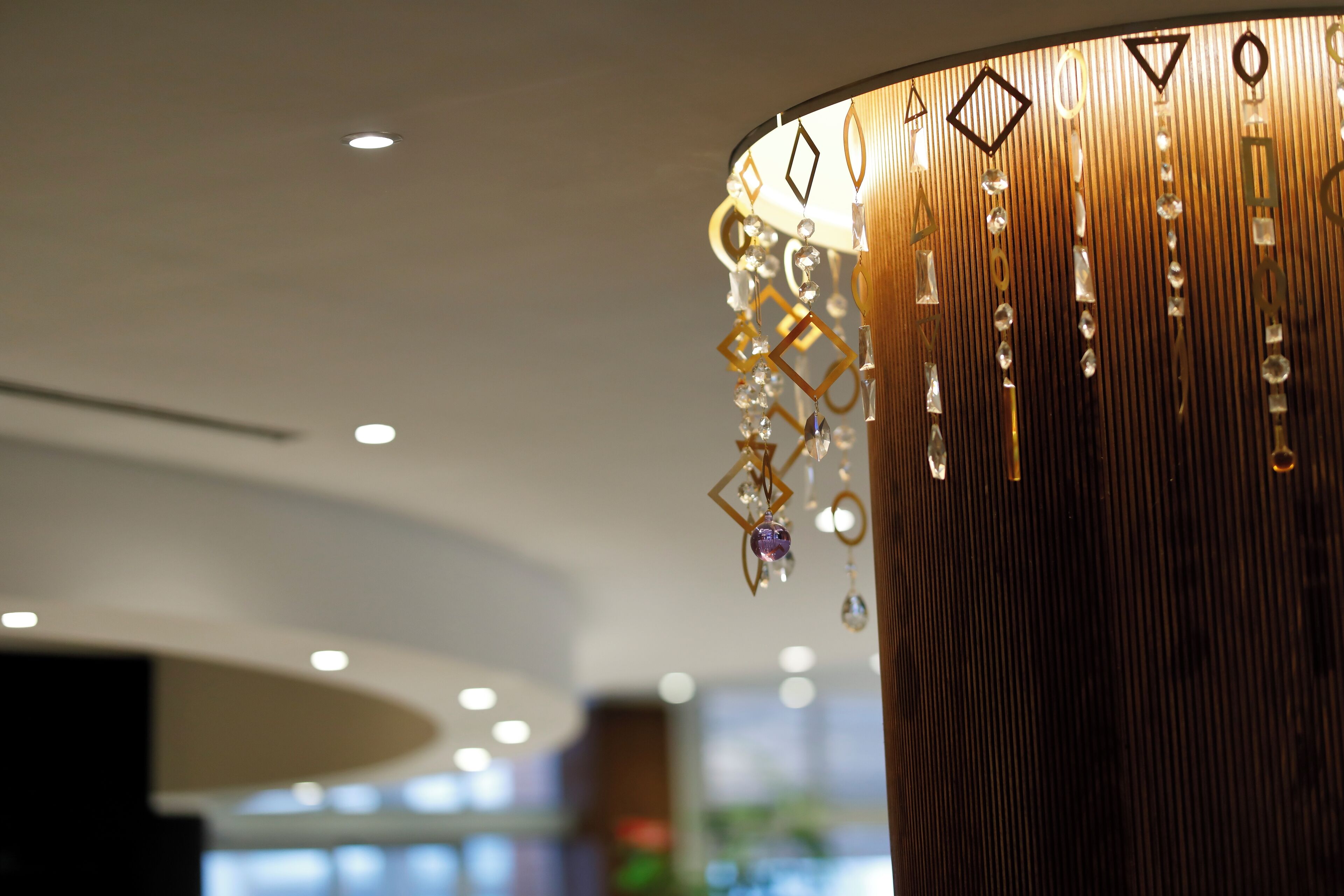 A modern interior with a wooden cylindrical column and hanging decorative elements.