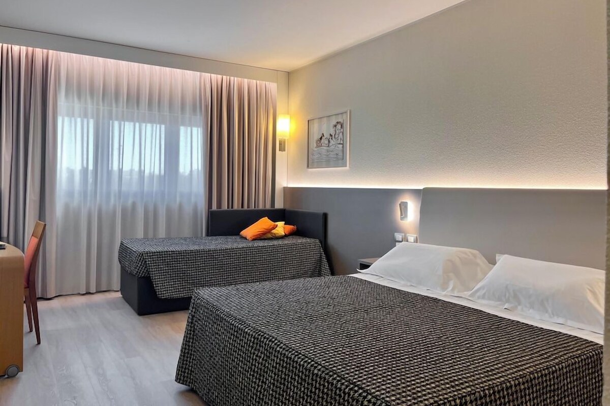 Une chambre d’hôtel avec deux lits, un bureau et une chaise.