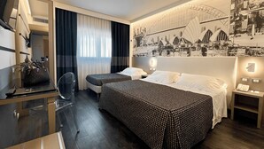 Een hotelkamer met twee bedden, een bureau met stoel, een spiegel, een raam met gordijnen en een muurschildering.