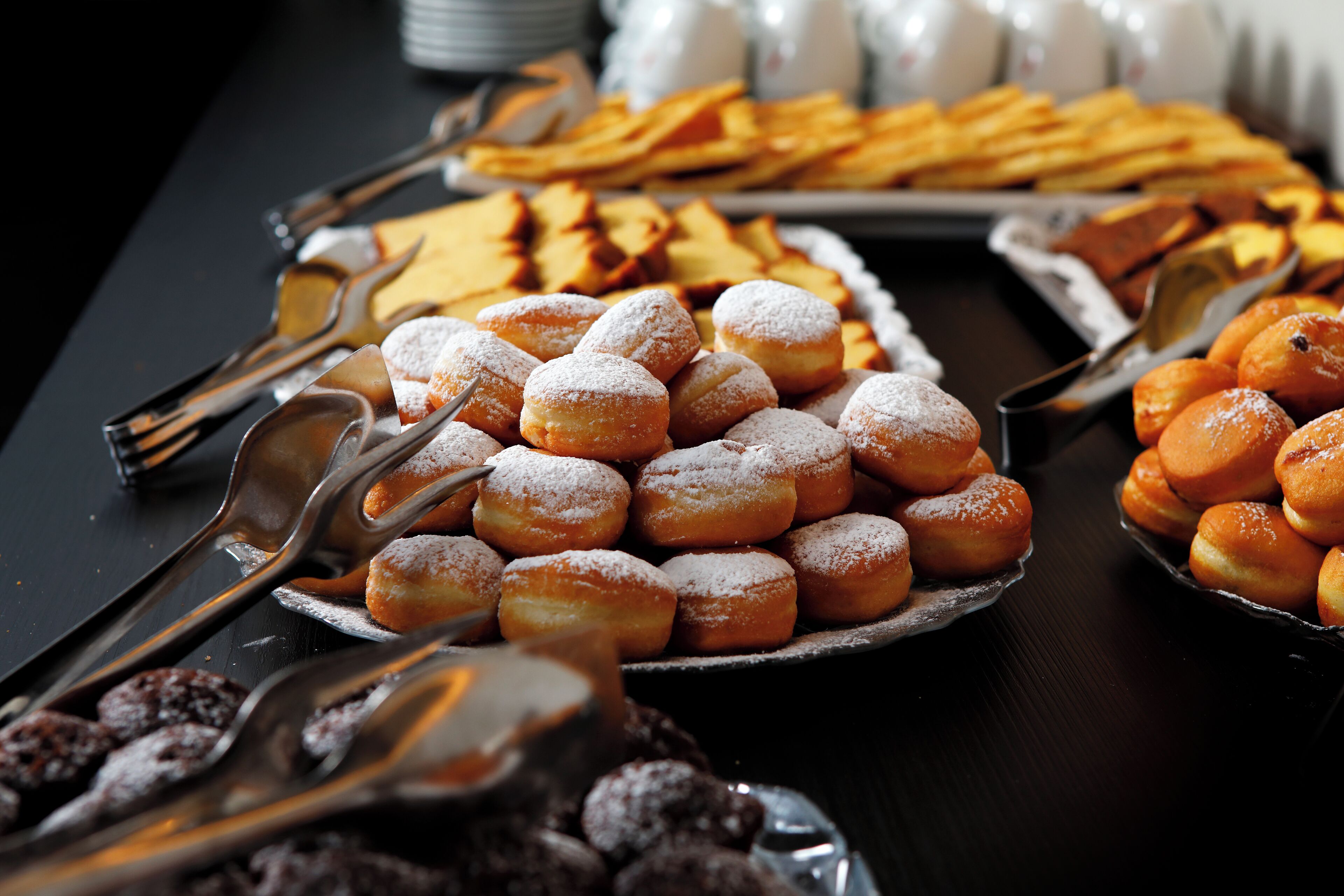 Une table de buffet proposant une variété de pâtisseries et de desserts, notamment des beignets et d’autres douceurs.