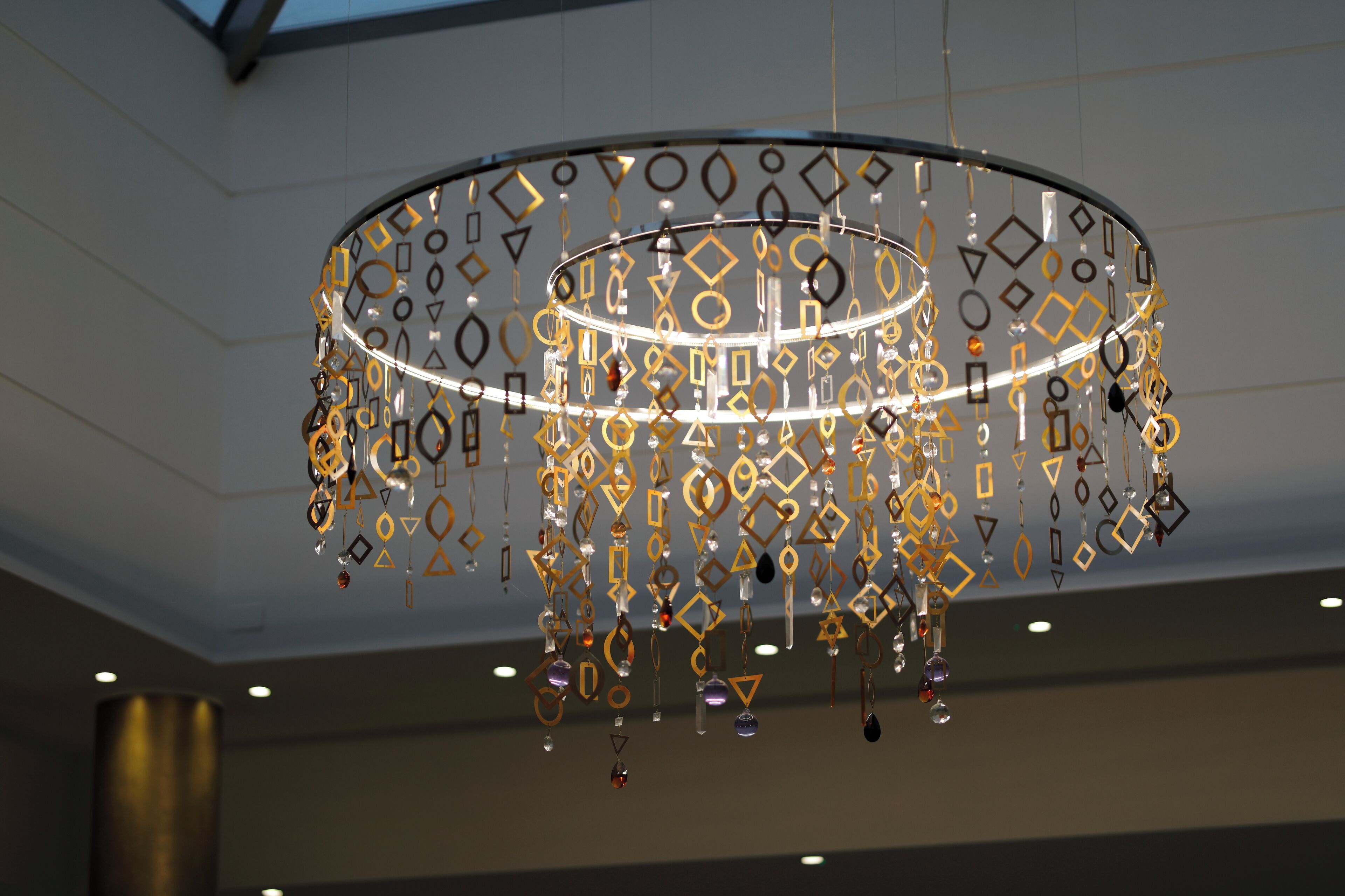 A modern chandelier with geometric patterns and hanging elements.