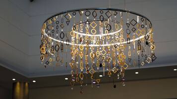 A modern chandelier with geometric patterns and hanging elements.