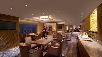 A hotel lobby with a dining area, a reception desk, and a buffet with fruit and beverages.