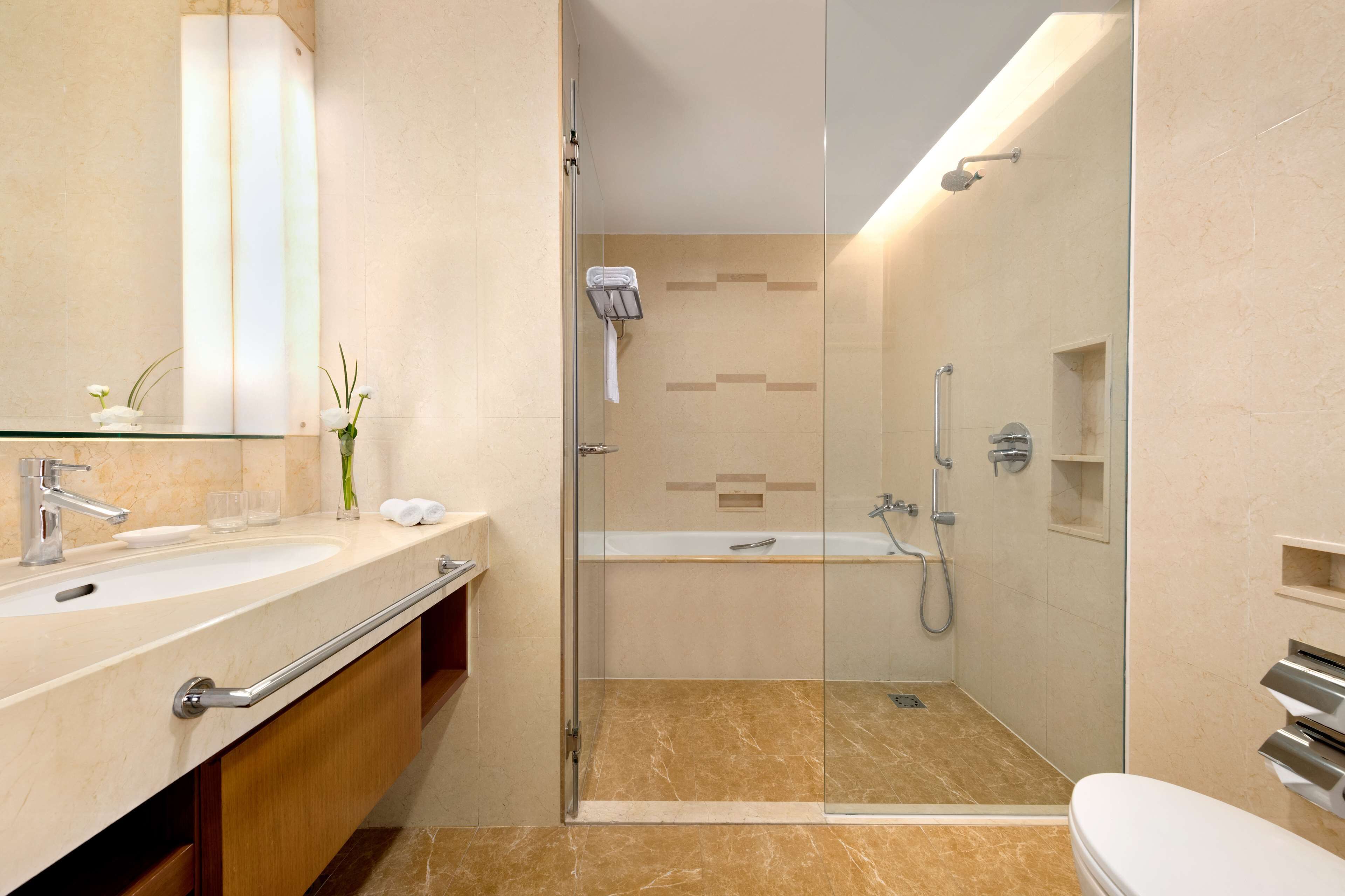 A modern bathroom with a glass-enclosed shower, a standalone toilet, and a vanity with a sink and mirror.