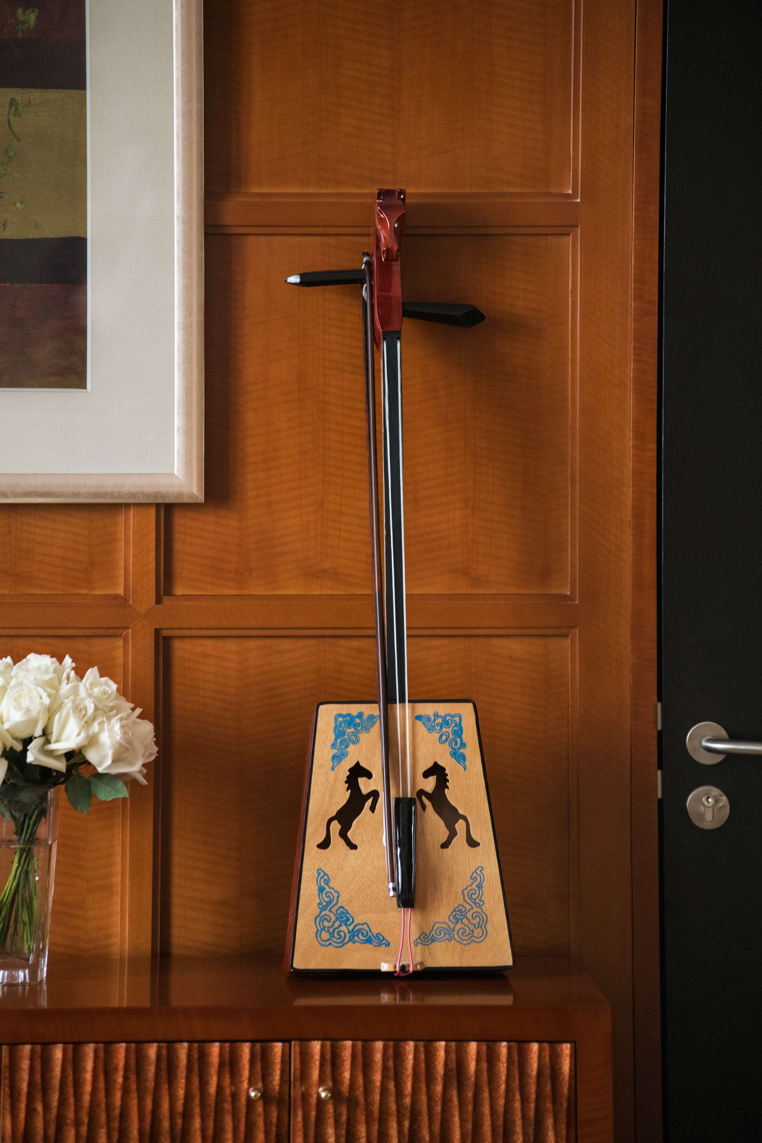 A wooden door with a framed picture above it and a small wooden plaque with a horse silhouette.