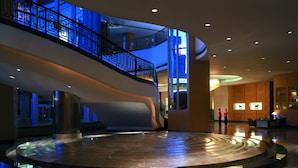 A spacious lobby with a central circular platform, a curved staircase, and a glass elevator. - Shangri-La Huhhot (Hohhot)