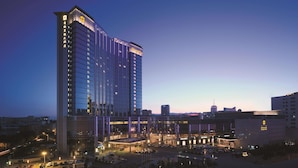 A high-rise hotel with a modern glass facade, multiple floors, and a prominent entrance area with a covered driveway. - Shangri-La Huhhot (Hohhot)