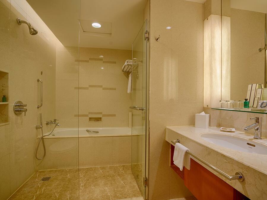 Un baño moderno con ducha envuelta en vidrio, una bañera independiente y un tocador con lavabo.
