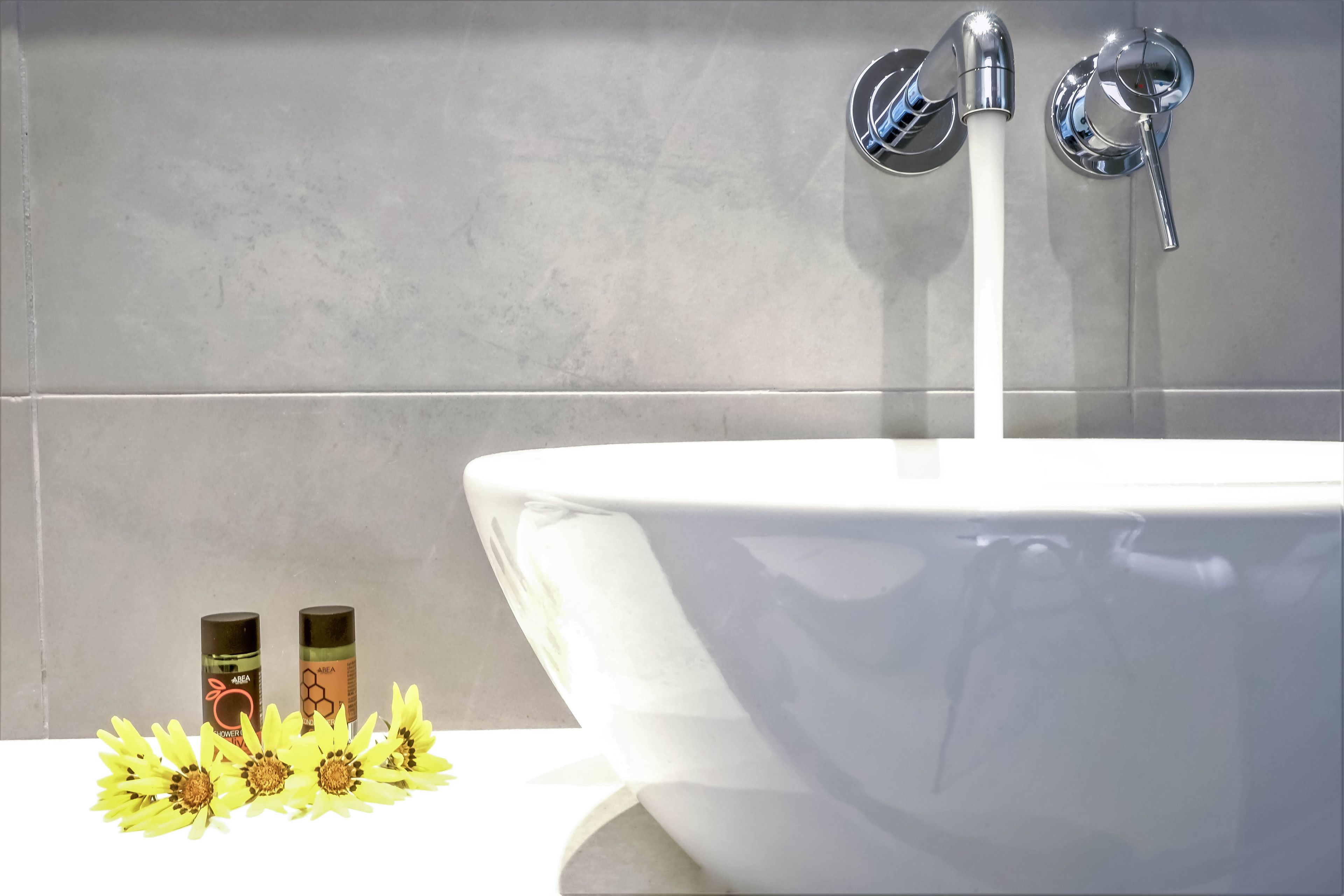 A bathroom with a white sink, two bottles of soap, and a faucet.
