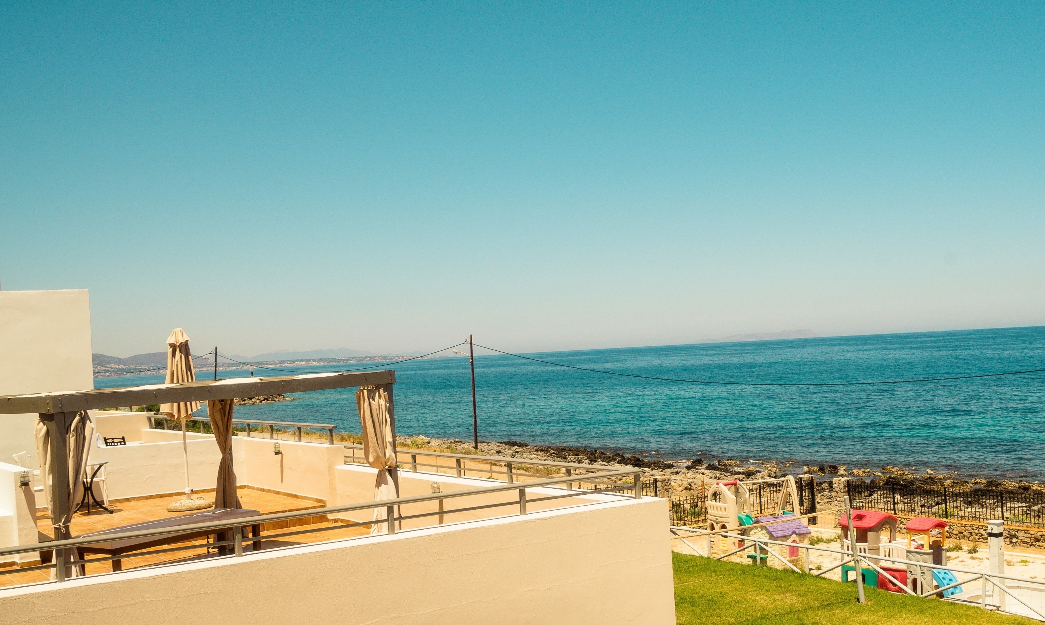 Vista de la playa con zona de juegos infantiles y una hamaca.