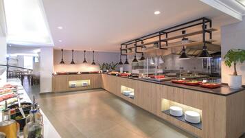 Una cucina moderna con isola centrale, illuminazione a sospensione e vista sull'area pranzo.