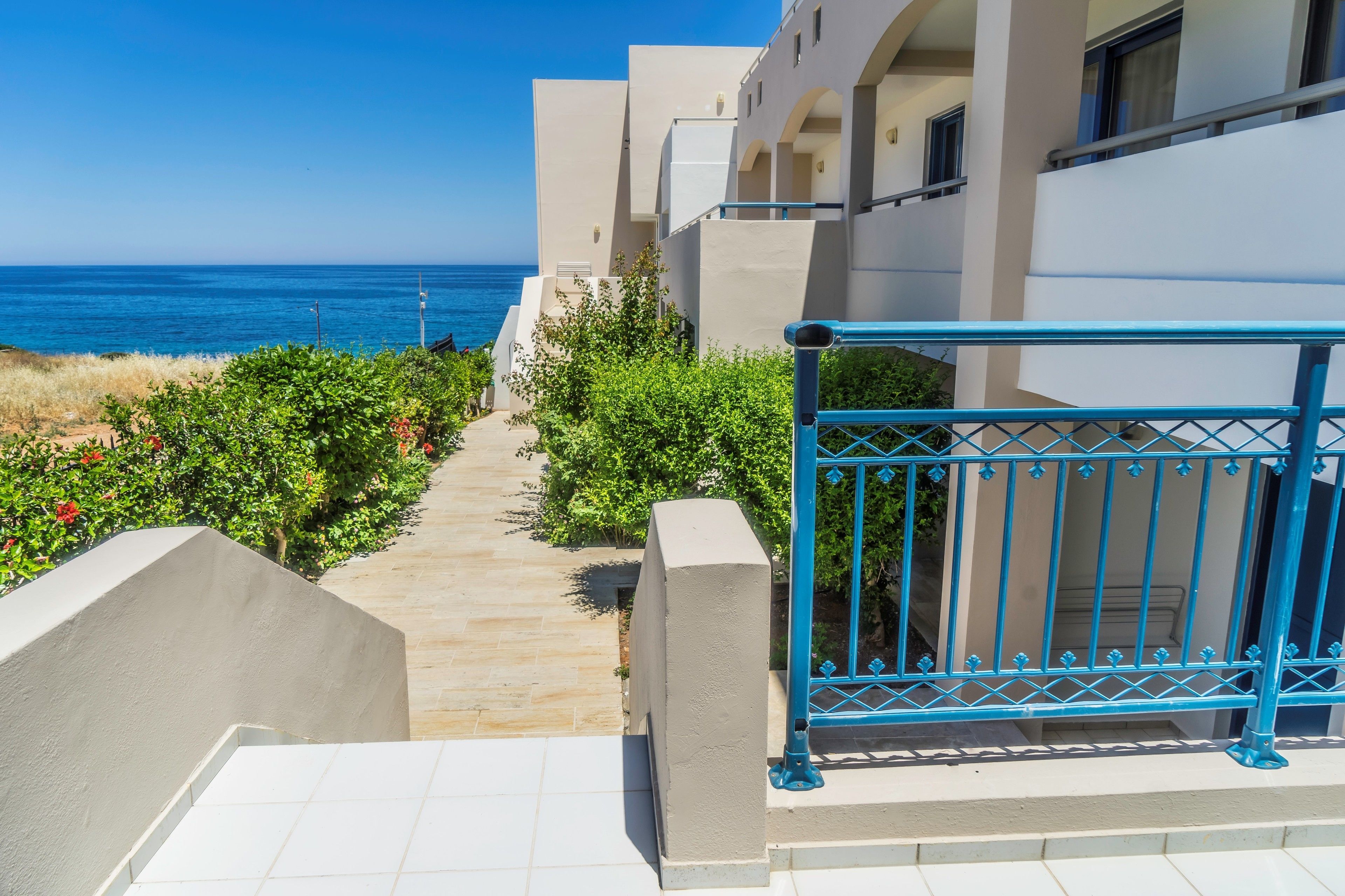 A pathway leading to a building with a view of the sea.