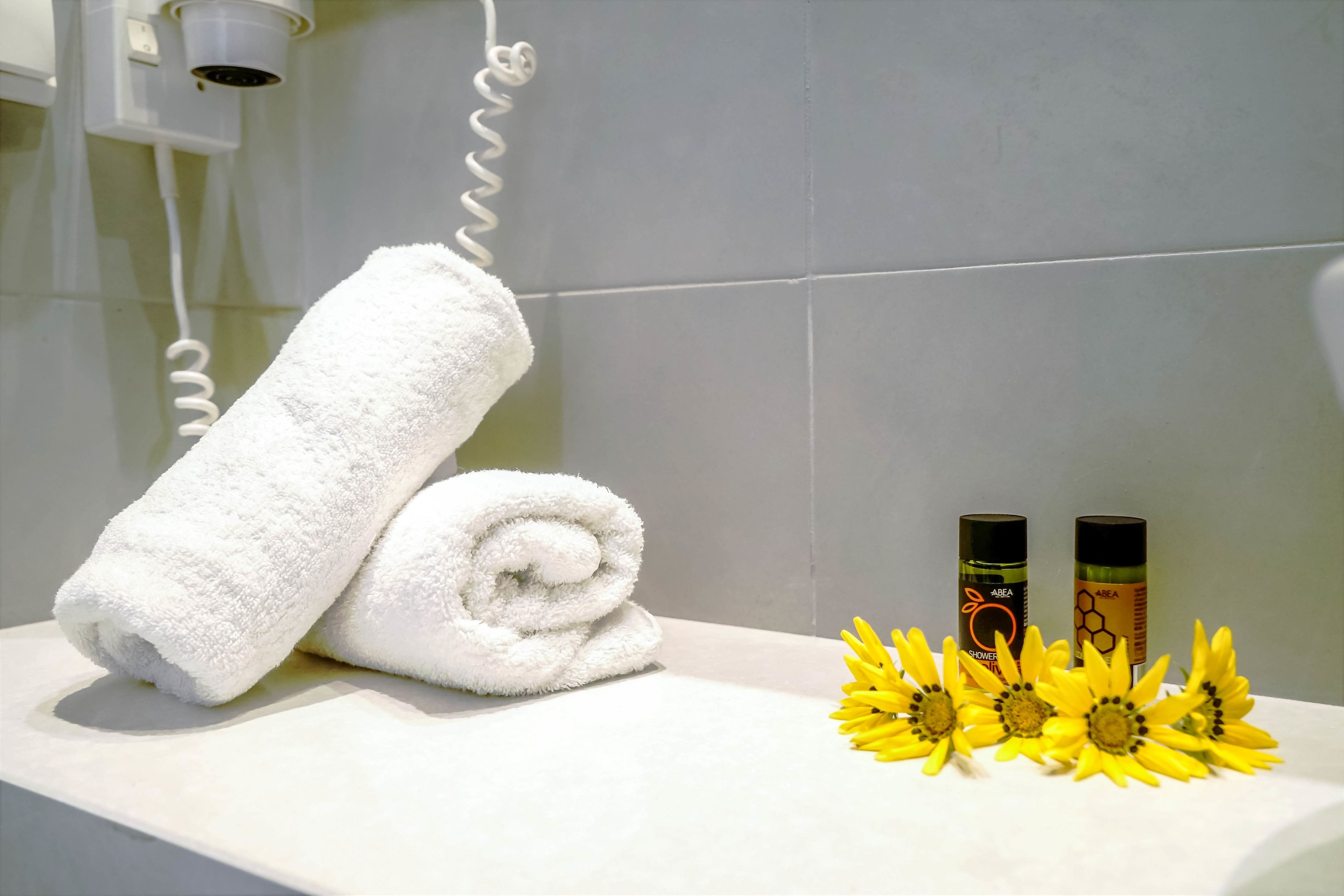 Ein Badezimmer mit Handtuch, zwei Pflegeflaschen und Sonnenblumen.
