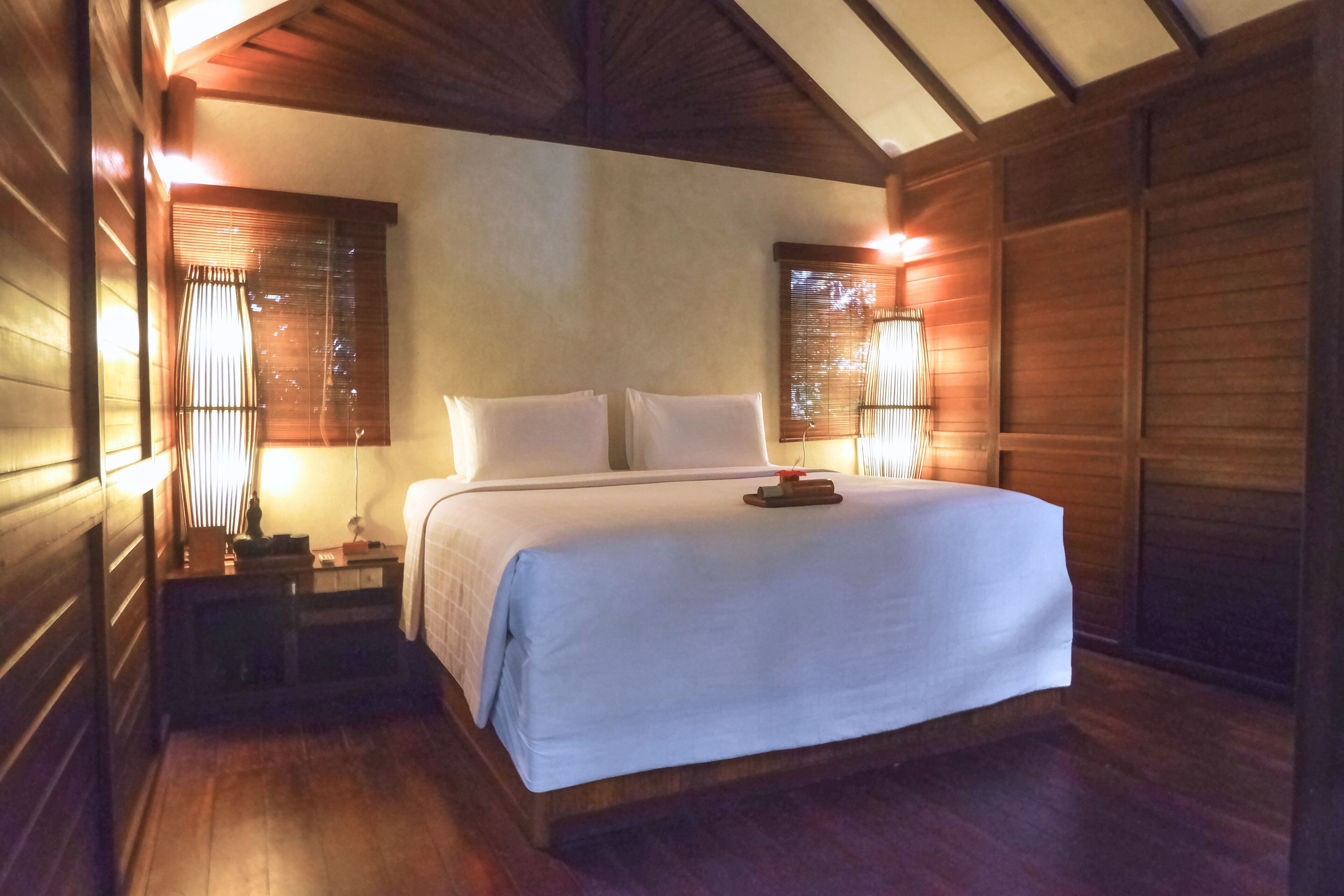 Una habitación de madera con una cama, mesitas de noche y lámparas.