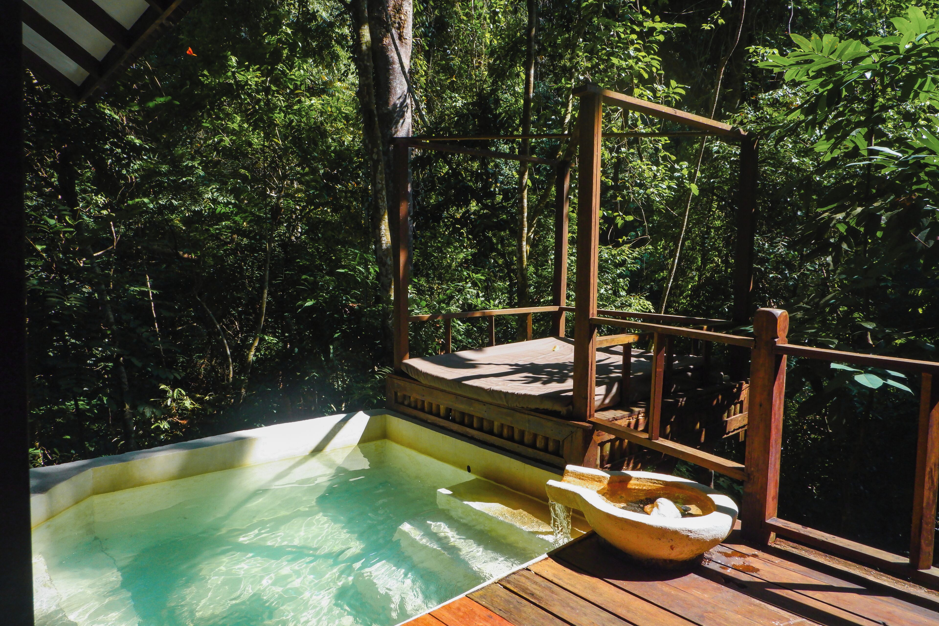 A hot tub surrounded by a wooden deck, set in a lush forest environment.
