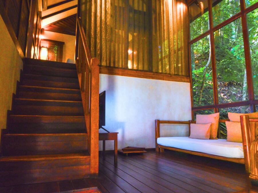 A wooden staircase leading to a room with a large window, a wooden bench, and a small table.