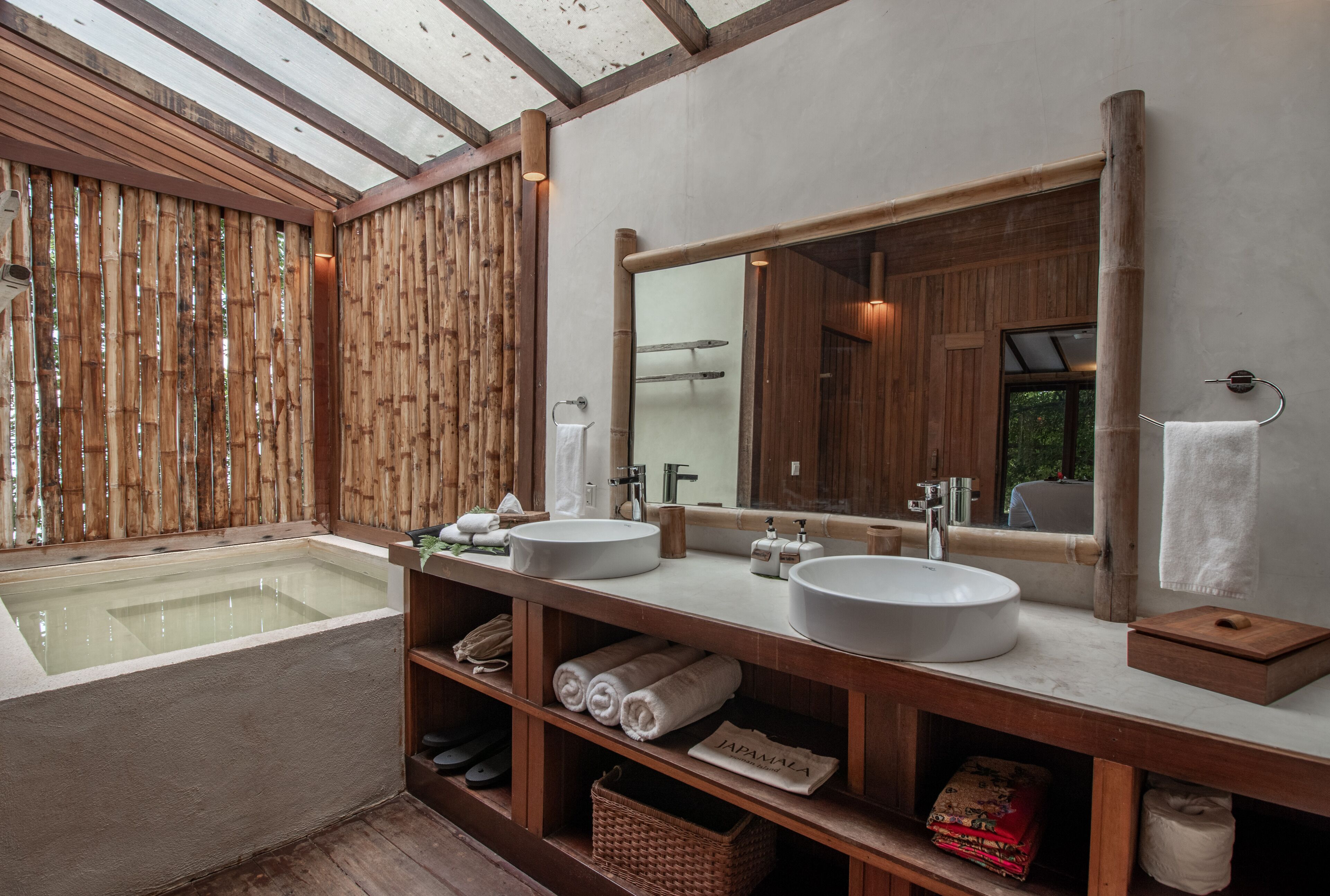 A modern bathroom with two sinks, a large mirror, and a wooden bath area.