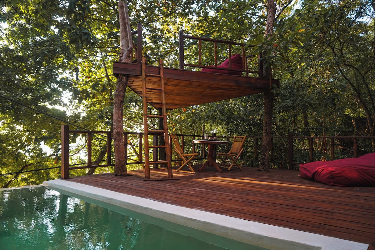 A wooden deck with a pool, surrounded by trees.