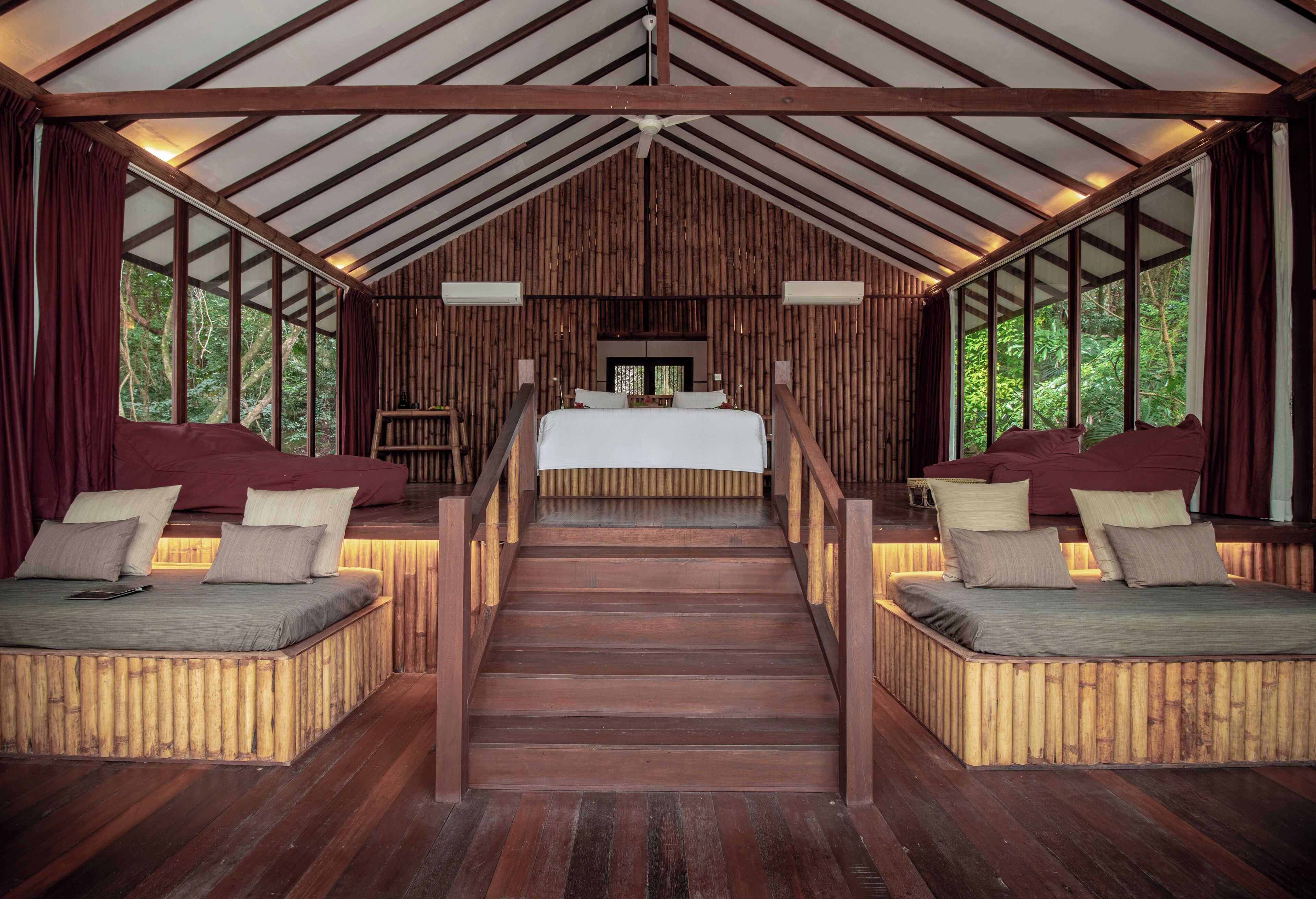 A spacious room with a large bed, two smaller beds, and a staircase leading to a loft area.