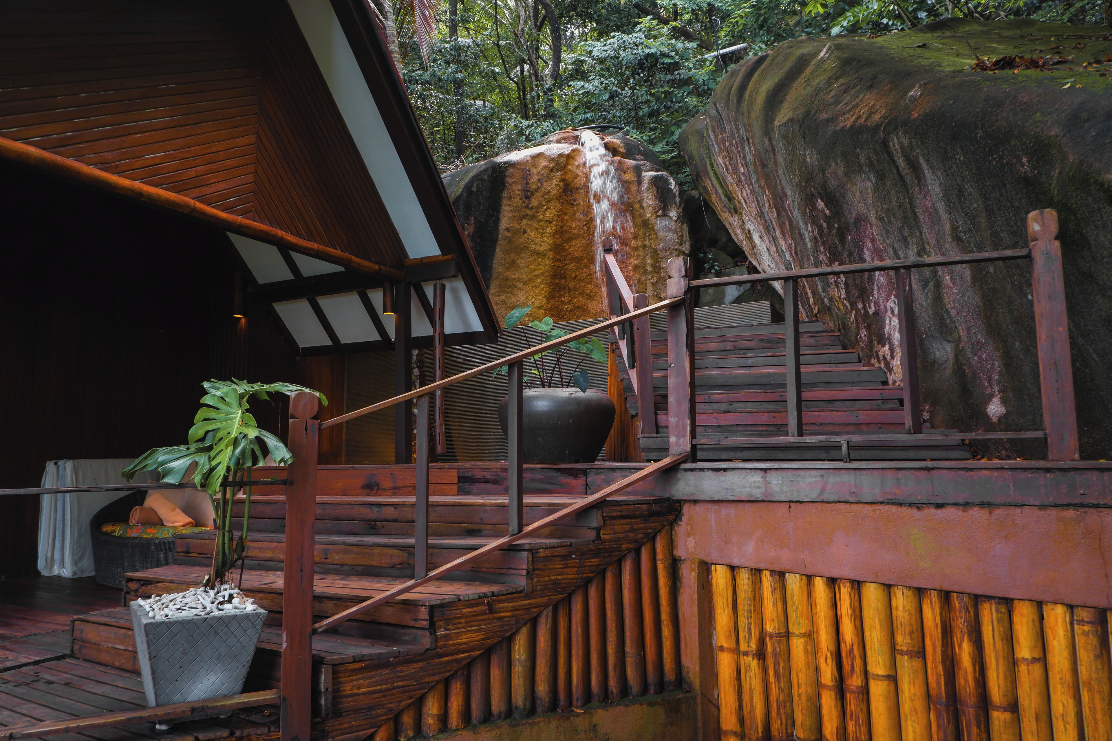 A wooden staircase leading to a wooden deck with a large planter and a potted plant.