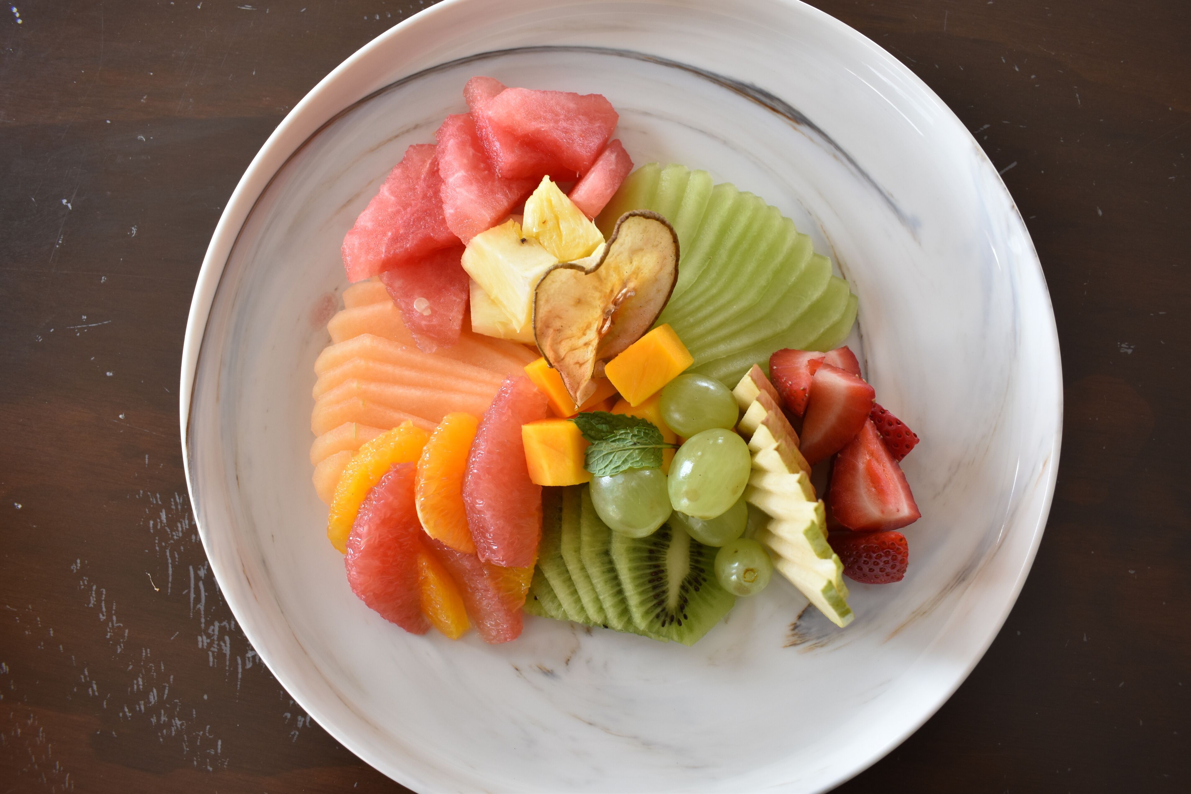 A bowl of assorted fruits including watermelon, kiwi, grapes, and mango.