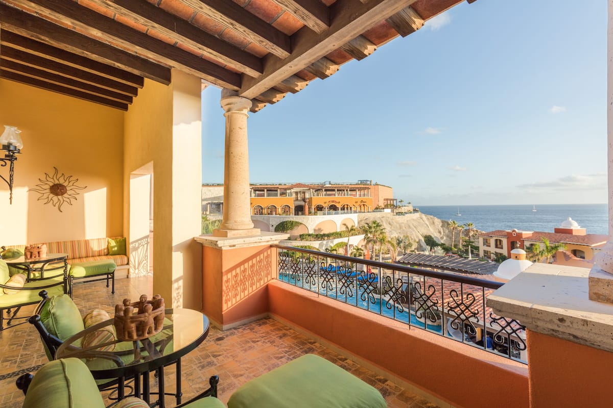 Uma varanda com vista para o mar, uma piscina e um edifício com arcos.