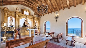 An interior with wooden pews, a central altar, and a view of the sea through an arched window. - Hacienda Encantada Resort & Residences (Cabo San Lucas)