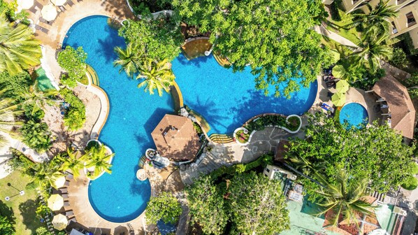 An aerial view of a resort with multiple swimming pools surrounded by lush greenery and palm trees. - Horizon Karon Beach Resort & Spa (Karon)