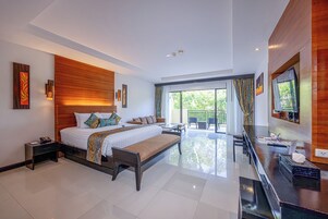 A modern hotel room with a large bed, a bench, a desk, and a balcony with a view.