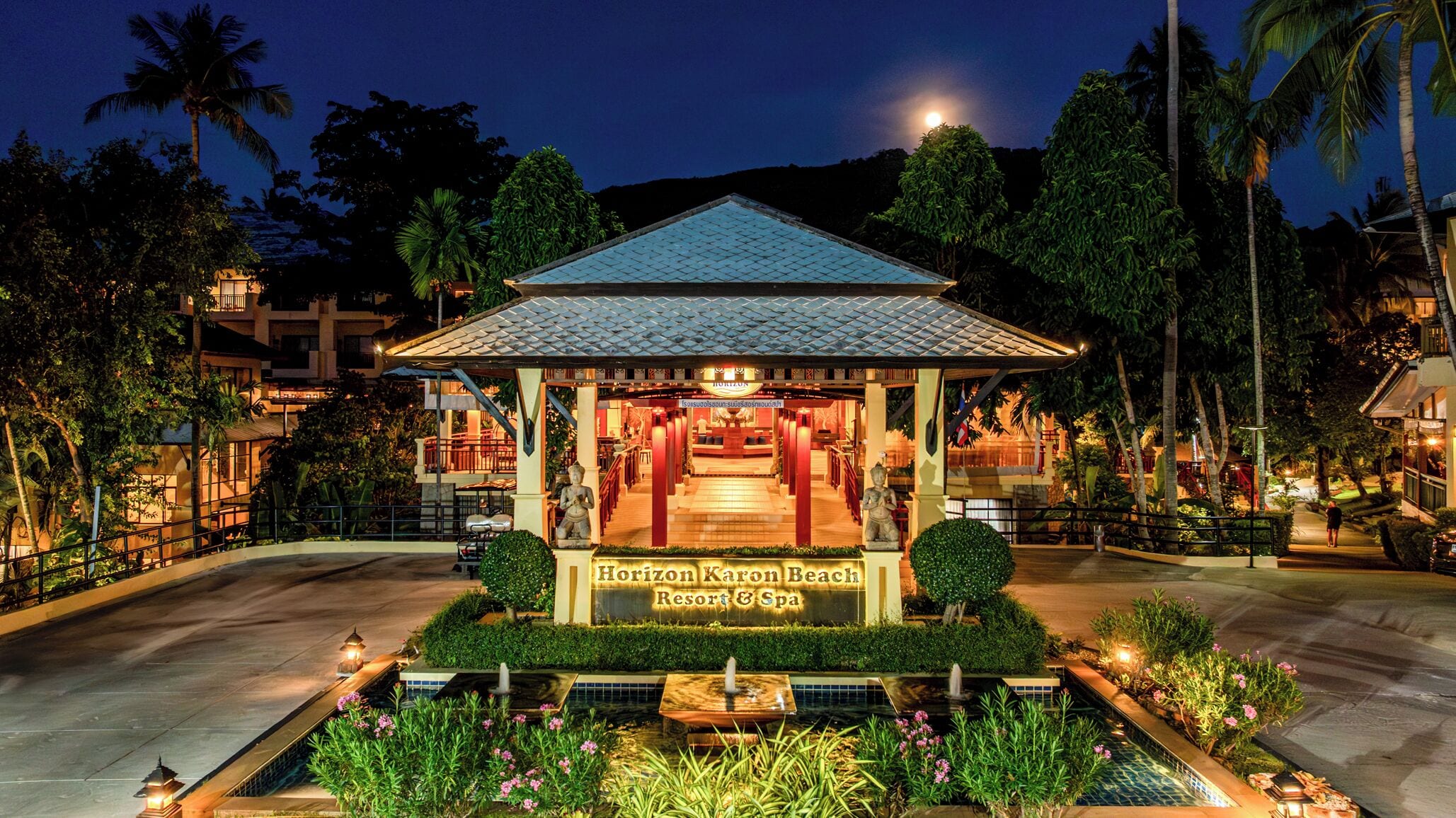 A resort with a covered entrance, a sign reading 'Horizon Karon Beach Resort & Spa,' and a water feature in the foreground.