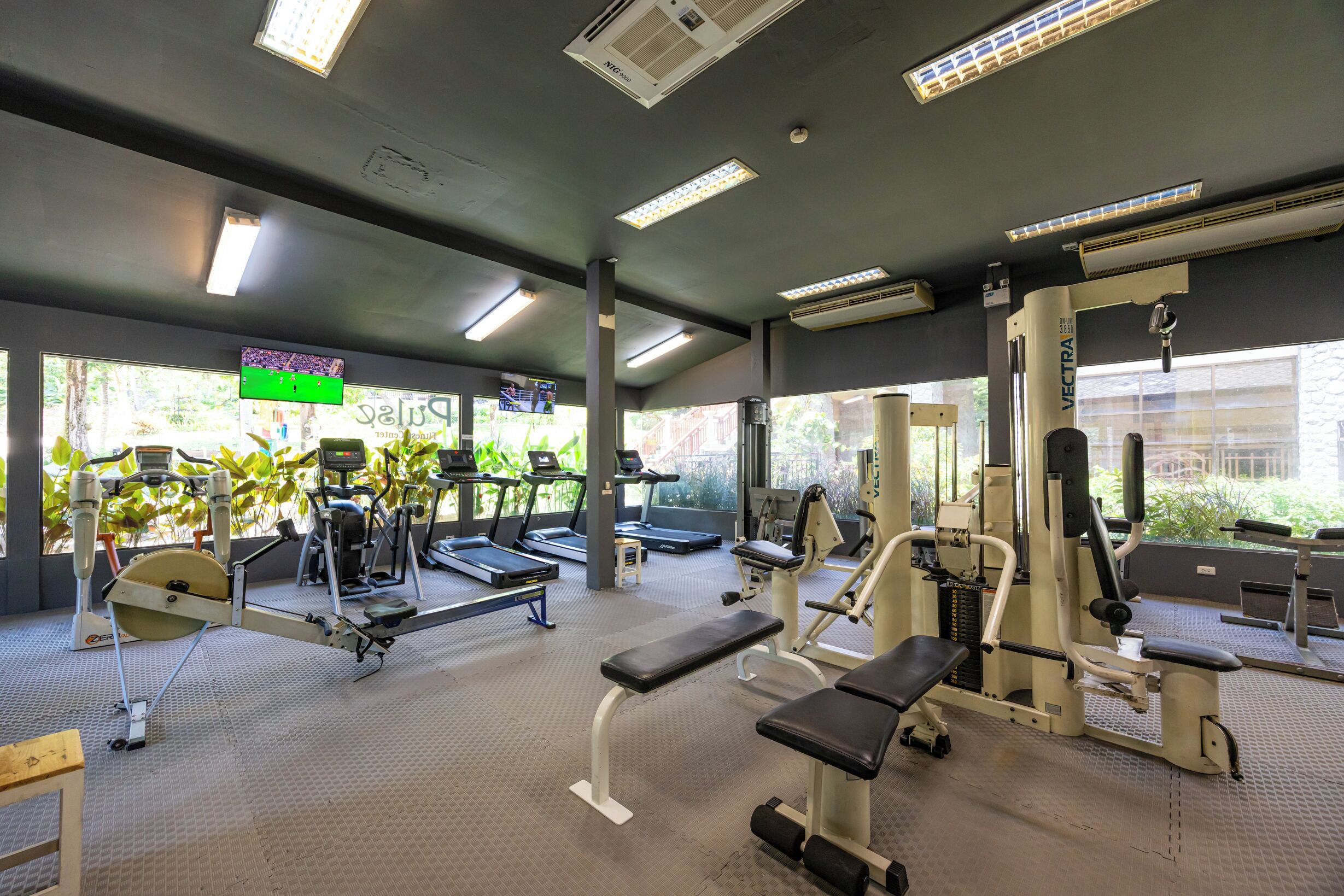 A gym with treadmills, weight machines, and benches.