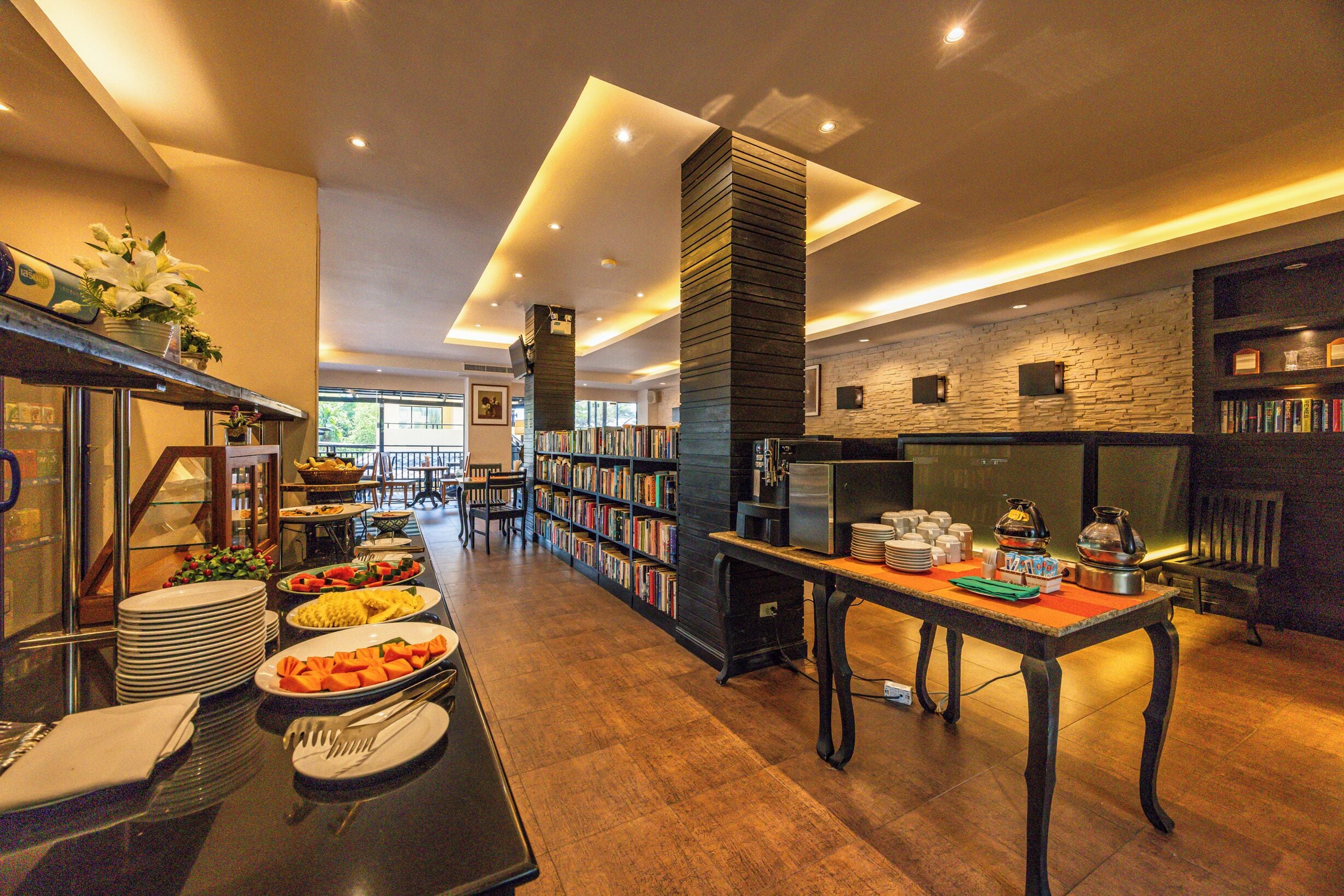 A modern hotel lobby with a buffet area, bookshelves, and a fireplace.
